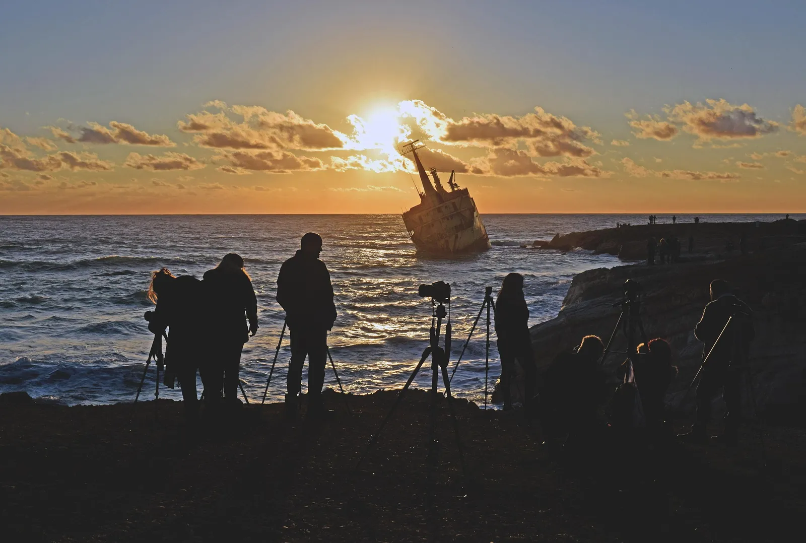 Photographers with tripods at sunset by the sea